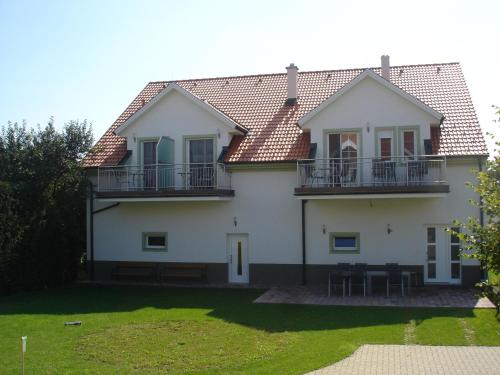 a white house with two balconies and a yard at Illmitzer Weinhof Haider in Illmitz