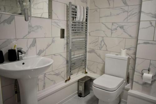 bagno bianco con servizi igienici e lavandino di Tottenham Hotspurs Stays at the Gascoigne Suite a Londra