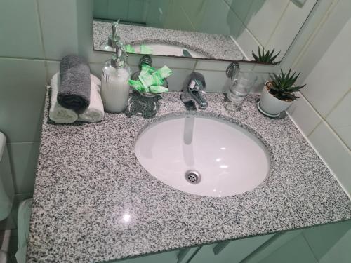 een badkamerbar met een witte wastafel en een spiegel bij Acogedor Departamento centrico in Cochabamba