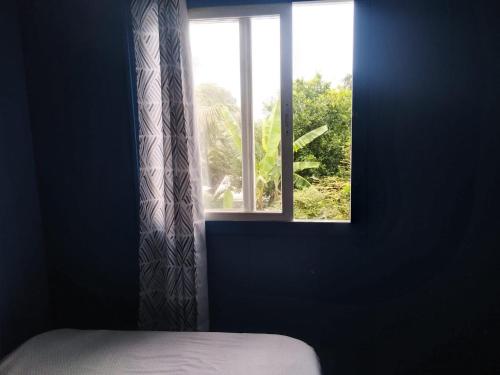 ventana en una habitación con cama y cortina en Ian Creole Garaden Cottages, en Roseau