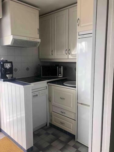 une cuisine avec des armoires blanches et un réfrigérateur blanc dans l'établissement Agde : appartement vue sur le port, au Cap d'Agde