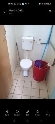 a bathroom with a toilet and a red bucket at Dena Moon inn in Kota Bharu