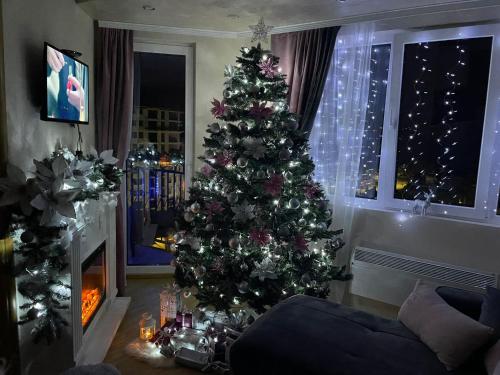 a christmas tree in a living room with a fireplace at Apartman sa ljuljaskom in Zlatibor