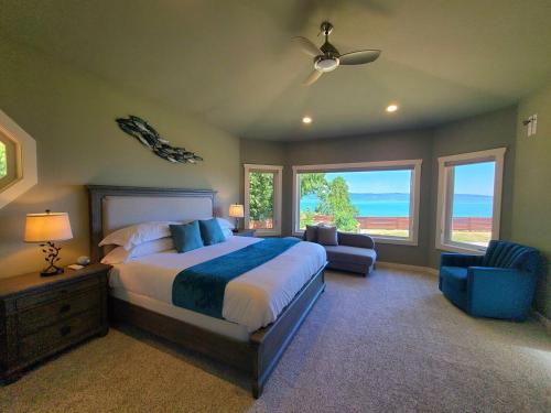 ein Schlafzimmer mit einem Bett, einem Sofa und Fenstern in der Unterkunft New Lighthouse Port Susan View House Camano in Bretland