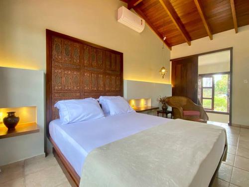 a bedroom with a large bed with a wooden headboard at Casa de Novela in Pirenópolis