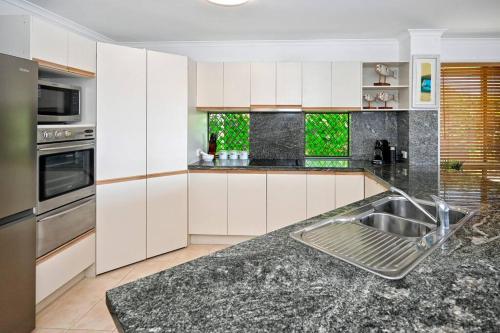 a kitchen with white cabinets and a stainless steel sink at Sunshine Coast Dream Getaway in Pelican Waters