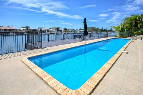 a swimming pool with blue water in front of a fence at Sunshine Coast Dream Getaway in Pelican Waters