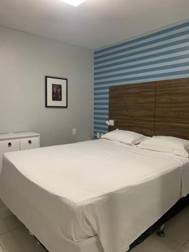 een groot wit bed in een slaapkamer met een blauwe muur bij Iracema Residence Flat - Apto Particular in Fortaleza