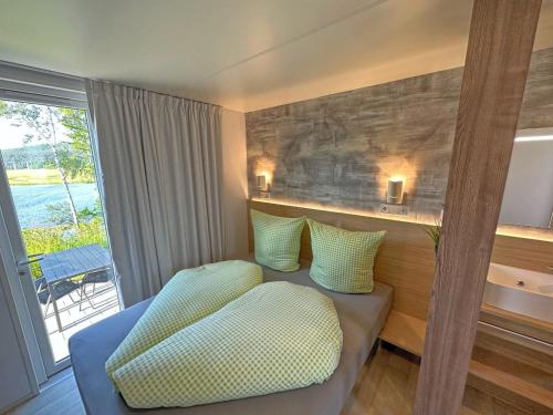 a hotel room with a couch and a window at Tiny chalets with terrace right on the lake in Neunburg vorm Wald