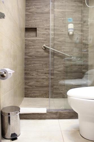 y baño con ducha de cristal y aseo. en Agora Suites Self-Service Boutique Hotel, en Bogotá