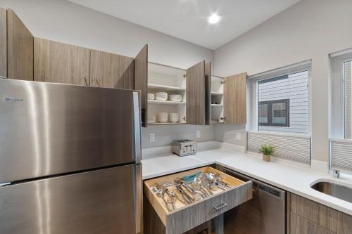 a kitchen with a stainless steel refrigerator and wooden cabinets at BRAND NEW Fully Updated Condo 918 in Anacortes in Anacortes