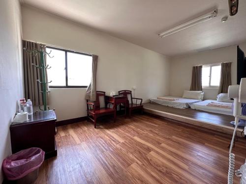Habitación con 2 camas y suelo de madera. en 丸松商旅, en Miaoli