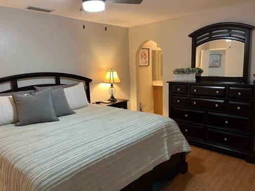 ein Schlafzimmer mit einem Bett, einer Kommode und einer Lampe in der Unterkunft Palaco Paradise, Canal View and Pool in Cape Coral
