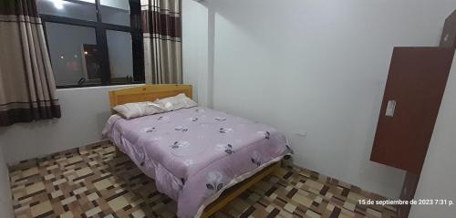 Dormitorio pequeño con cama con edredón púrpura en Hostal Pura Casta en Carhuaz