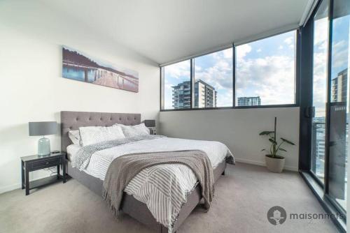Un dormitorio con una cama grande y grandes ventanales. en Mod Brisbane Apt near Southbank W Pool & Parking, en Brisbane