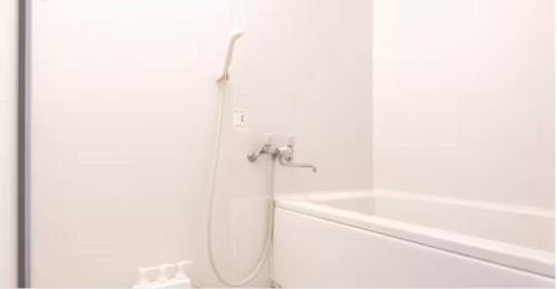y baño blanco con ducha y manguera. en メゾン・ド・ミナ, en Tokio