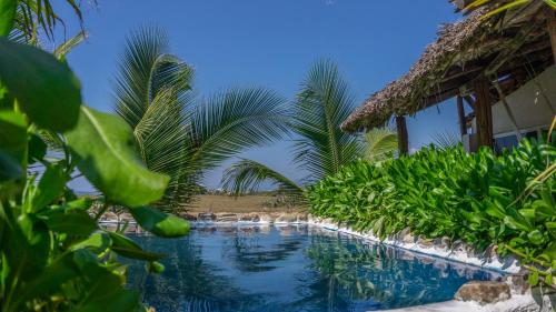 una piscina resort con palmeras en el primer plano en Sunset Beachside Villa, en Puerto Escondido
