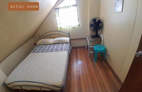a small attic room with a bed and a window at Amara Transient House - Homestay in Baguio