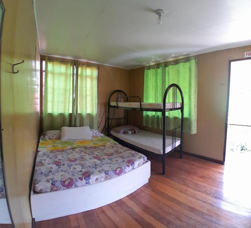 1 dormitorio con 2 literas y cortinas verdes en Amara Transient House - Temporary NO PARKING for June and July, need to walk 150meters, en Baguio