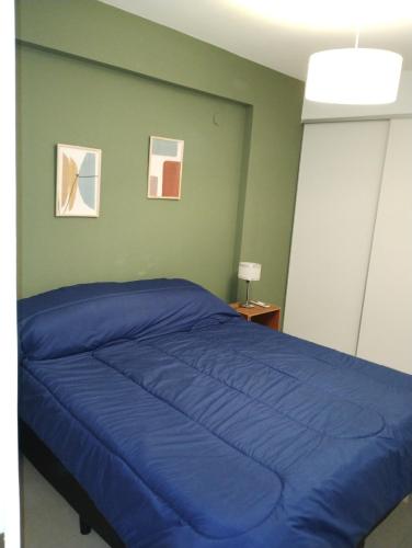 a bedroom with a blue bed with two pictures on the wall at Departamento Centro de Santiago del Estero in Santiago del Estero