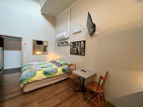 um quarto com uma cama, uma mesa e cadeiras em Westside Studio Apartments em Armidale