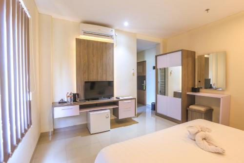 a room with a bed and a television in it at Canggu Dream Village Hotel and Suites in Canggu