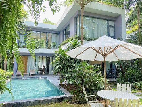 a house with a swimming pool and an umbrella at TD Villa- Dai Lai Resort in Phúc Yên