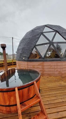 a hot tub on a wooden deck with a building at Domos Maran Lican Ray in Licán Ray