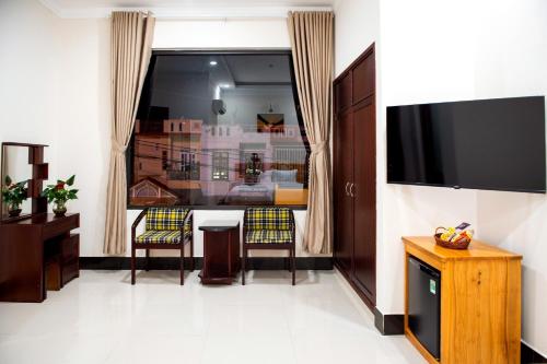 a living room with a television and a table and chairs at MINH LÂM HOTEL in Pleiku