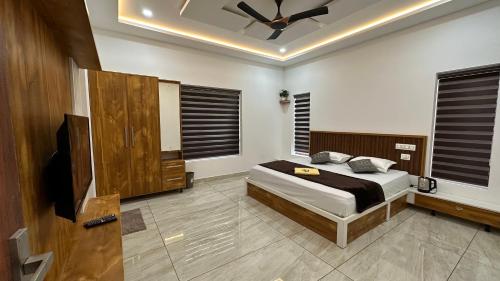 a bedroom with a bed and a ceiling fan at Rhythm Holiday Home in Sultan Bathery