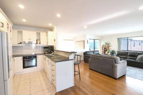 a kitchen and living room with a couch and a table at Beech Break - 3 bedroom pet friendly apartment in Merimbula