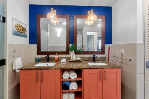 a bathroom with two sinks and two mirrors at Lux Maho Reef 1BR Suite Condo next to The Morgan Resort in Maho Reef
