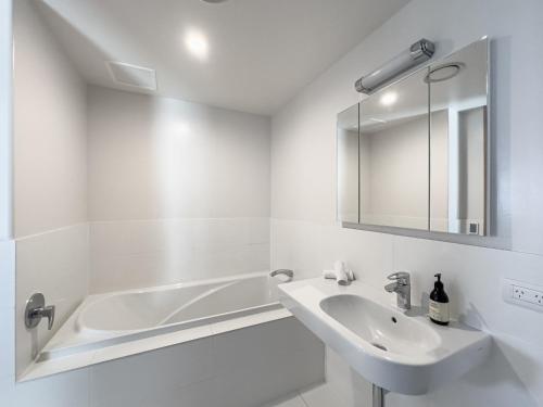 a white bathroom with a sink and a bath tub at Mount Eleven Fabulous Sea Views in Mount Maunganui