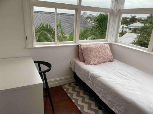 a small room with a bench and two windows at Grand villa plus studio in central location in Auckland