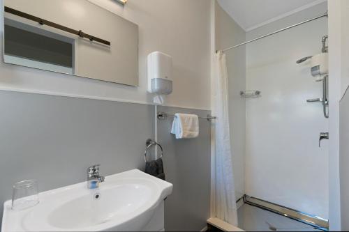 Central Inn Taupo في تاوبو: حمام أبيض مع حوض ودش