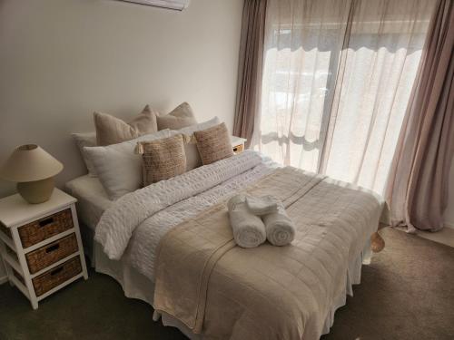 um quarto com uma cama branca e toalhas em Guest House on Guthrie em Havelock North