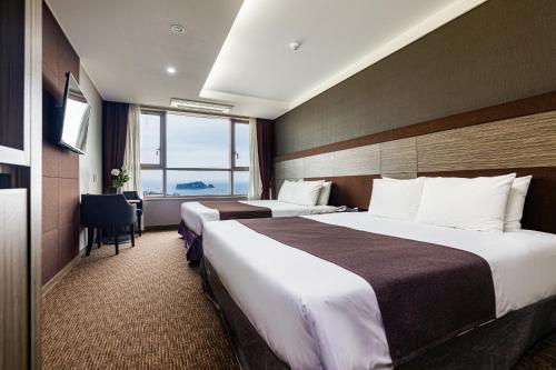 a hotel room with two beds and a window at Eastern Hotel Jeju in Seogwipo