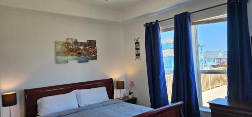 1 dormitorio con 1 cama con cortinas azules y ventana en PRIVATE BEACH -- AWAY FROM THE CROWDS - Ocean Views -Short drive to MOODY GARDENS, SCHLITTER BAHN, PLEASURE PIER, en Galveston