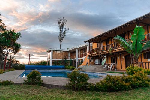 un complexe avec une piscine et un bâtiment dans l'établissement Hostería Colibri Aeropuerto, à Tababela