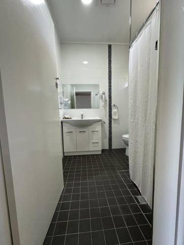 a white bathroom with a sink and a toilet at Bucketts Way Motel Gloucester in Gloucester