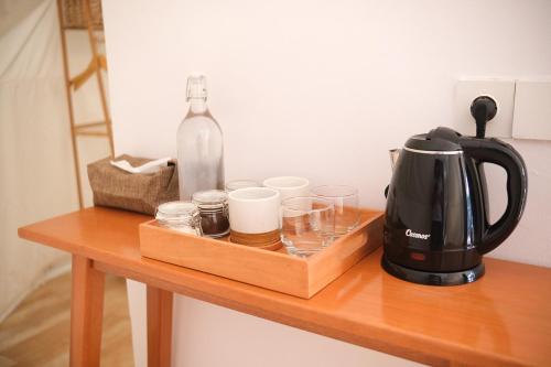 una cafetera y vasos sobre una mesa de madera en Ashamaya Belitung (Dome Glamping Site) en Pasarbaru