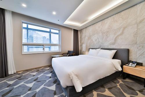 Un dormitorio con una gran cama blanca y una ventana en Hotel Haydn en Busan