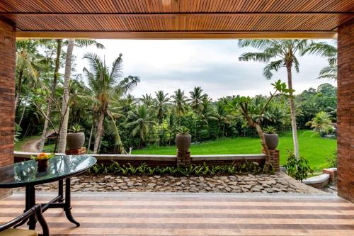 a patio with a table and a view of a garden at Umasari Rice Terrace Villa by AGATA in Tabanan