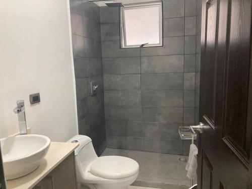ein Badezimmer mit einem weißen WC und einem Waschbecken in der Unterkunft Hermoso Apartamento en Alajuela in Alajuela