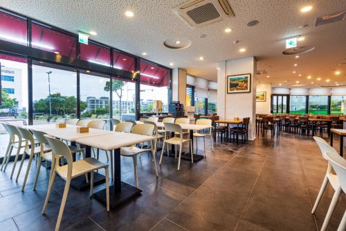 restauracja ze stołami, krzesłami i oknami w obiekcie Eastern Hotel Jeju w mieście Seogwipo