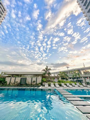 a swimming pool with chairs and a cloudy sky at UNIT B218 in Bacolod