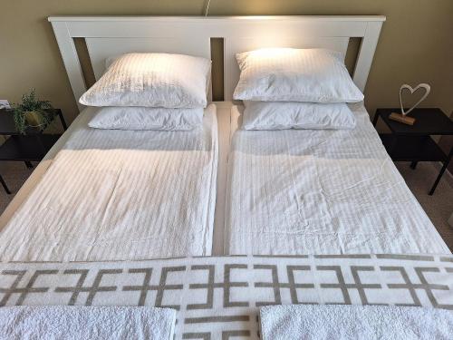 two beds in a room with white sheets and pillows at Kavics Apartman Tata in Tata