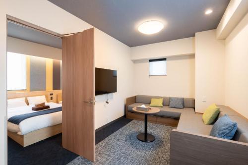 um quarto com uma cama, um sofá e uma televisão em stayme THE HOTEL Ueno em Tóquio