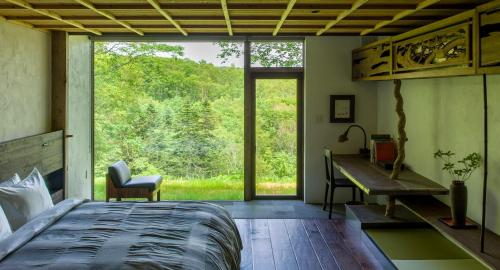 a bedroom with a bed and a desk and a window at SHIGUCHI in Kutchan