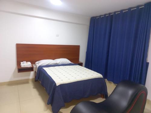 1 dormitorio con 1 cama, 1 silla y cortinas azules en HOSTAL VILLA REAL, en Lima